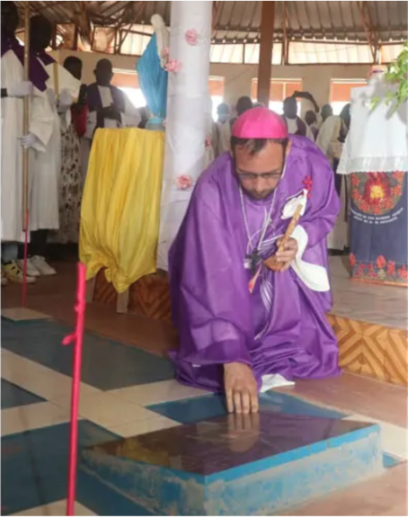 Bishop Christian Carlassare placing a cross on the grave of his predecessor the late Comboni Bishop Caesar Mazzolari in Holy Family Cathedral at a Mass following his episcopal ordination.
