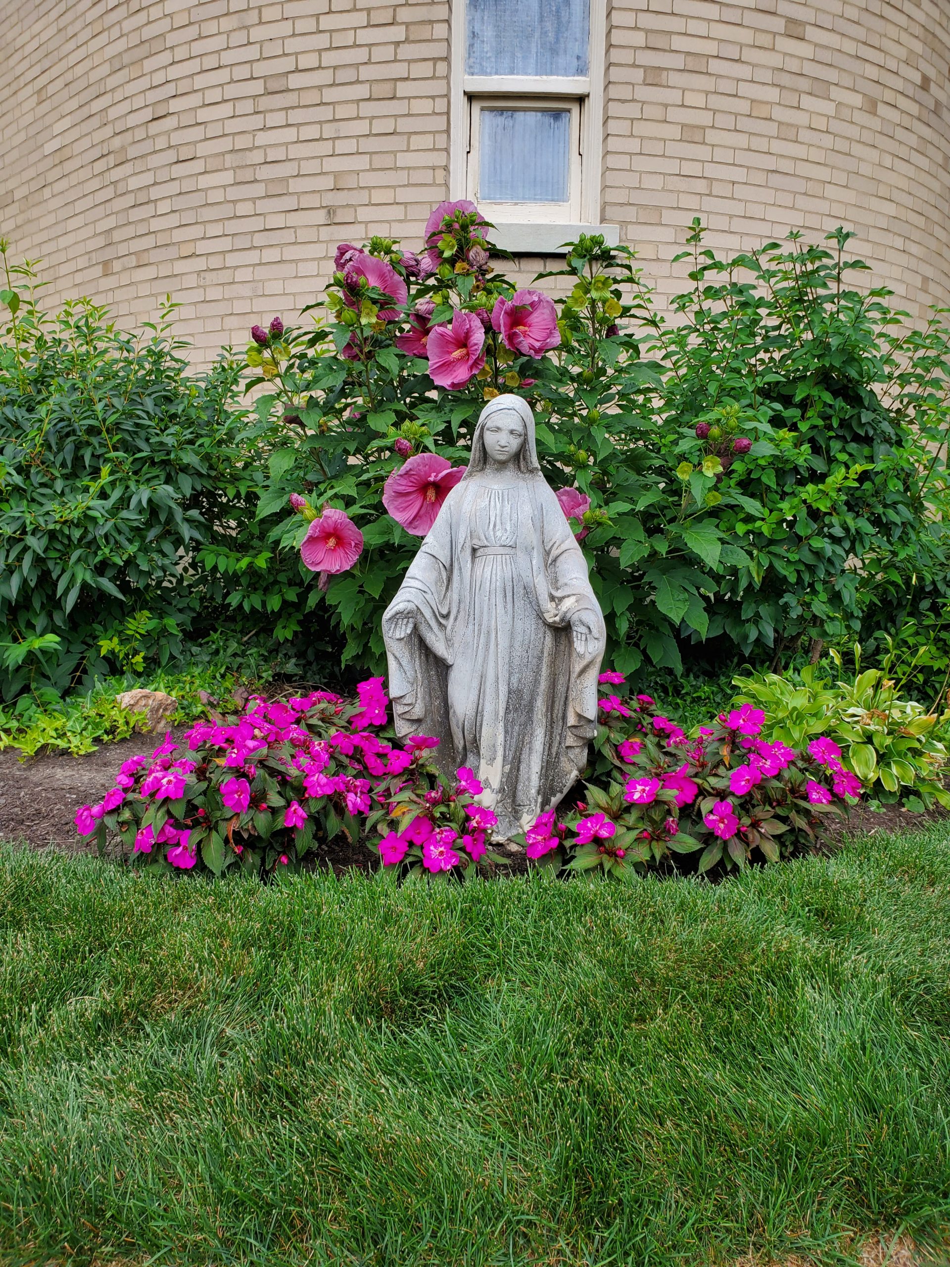 Statue of Mother Mary surrounded by pink flowers