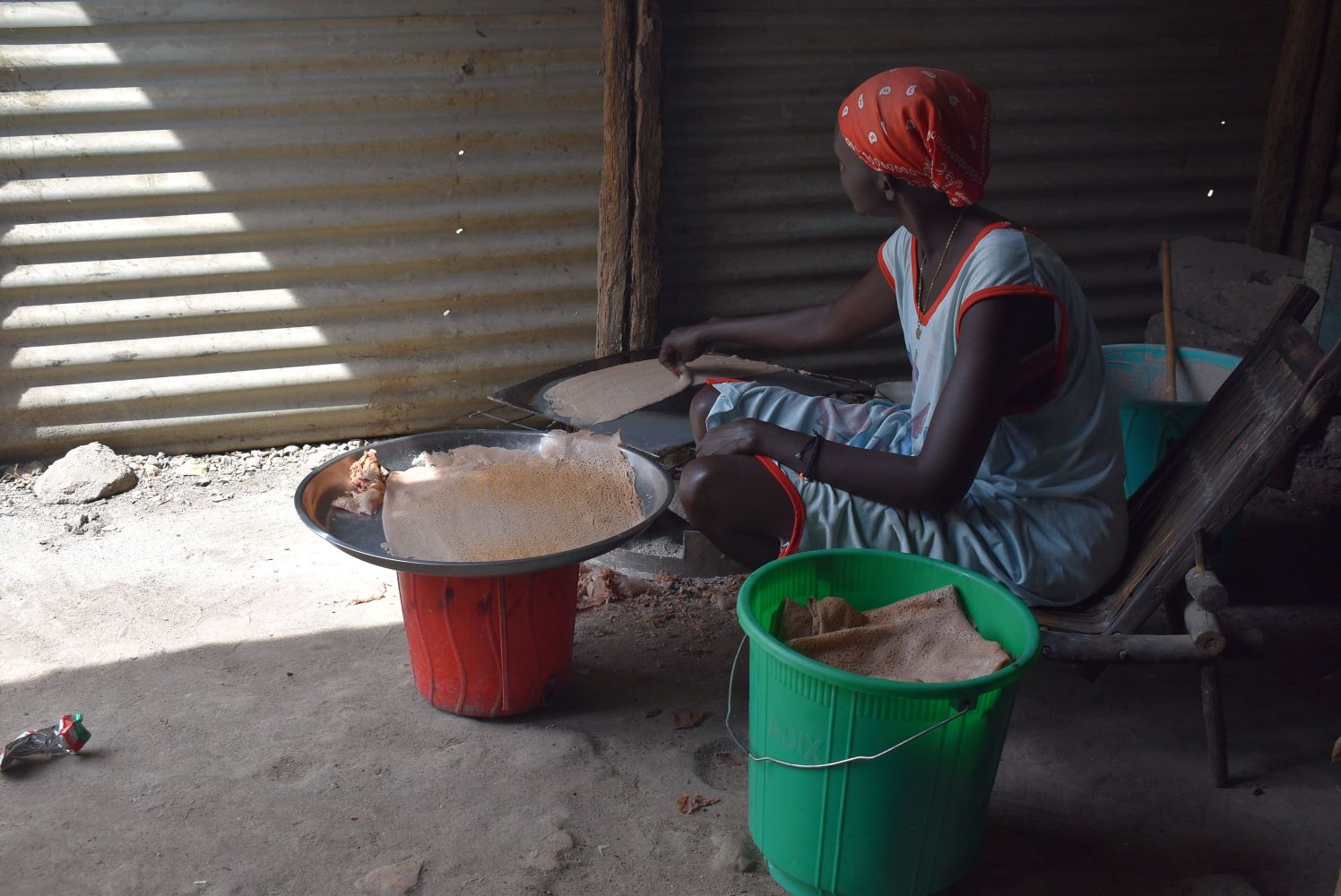 A young African woman prepares Kisra from sorghum grains.