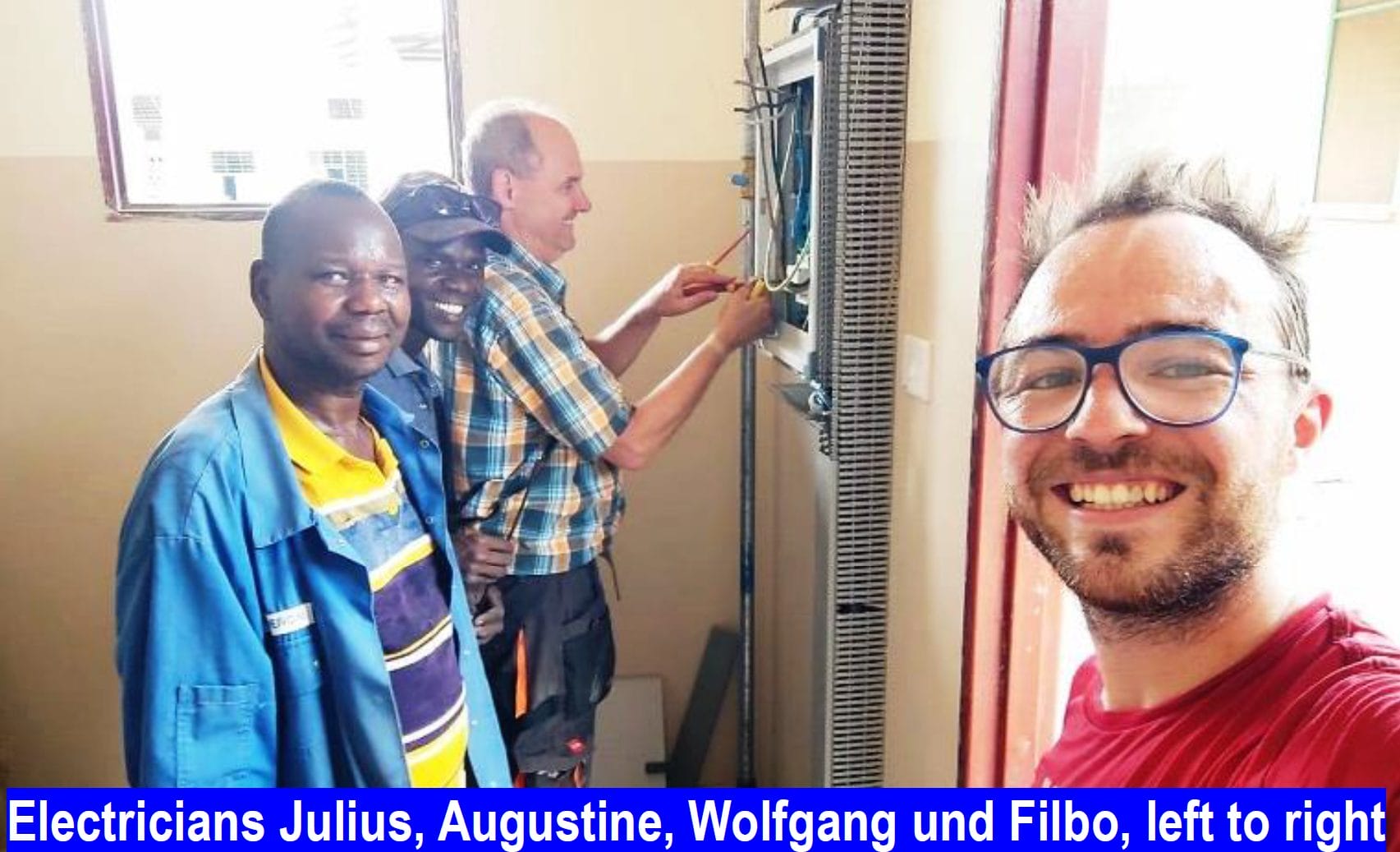 Three electricians work on an electrical panel