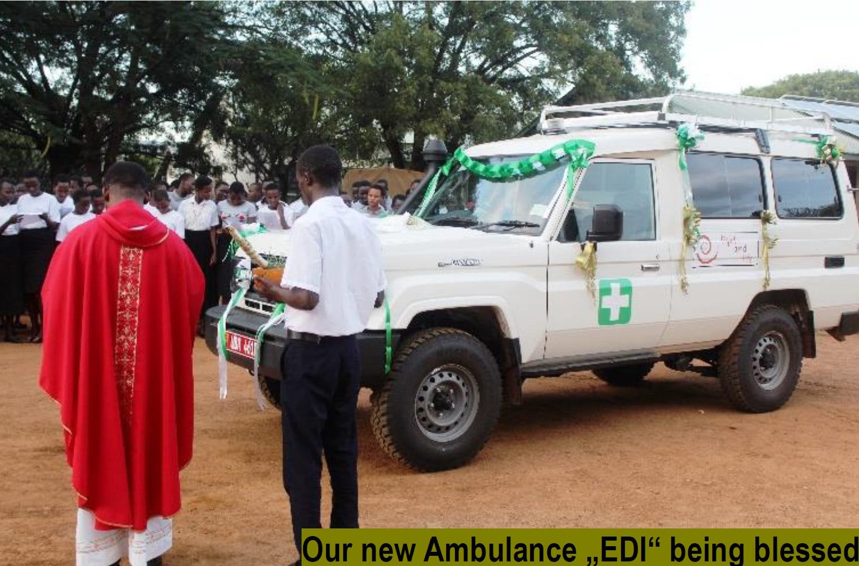 A priest in red vestments blesses a new ambulance