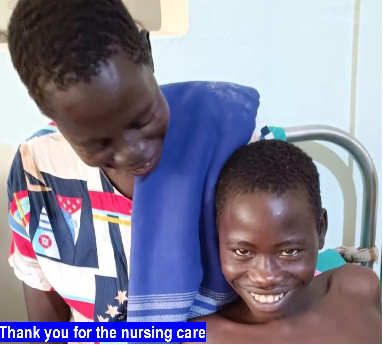 A black nurse looks at her patient, an adolescent black boy smiling broadly