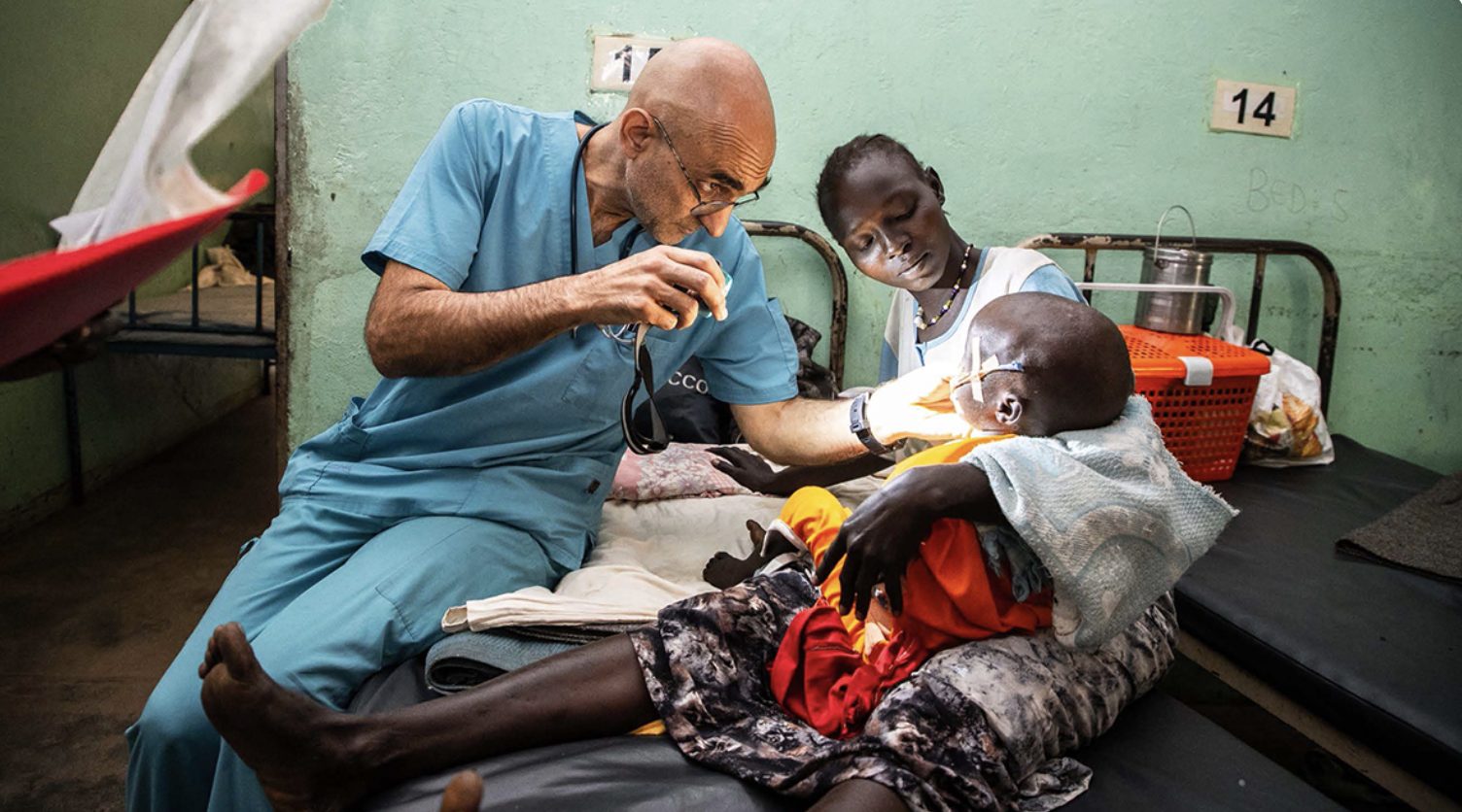 Dr. Tom Catena examines a child held by a woman in Sudan
